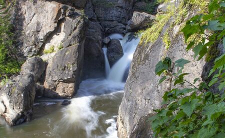 the beautiful small waterfall on the rapid river in the forestの写真素材