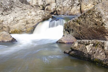 the beautiful small waterfall on the rapid river in the forestの写真素材