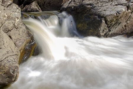 the beautiful small waterfall on the rapid river in the forestの写真素材