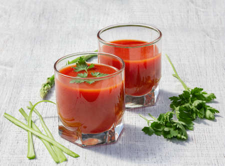 glasses are filled with tomato juice with parsley and celeryの写真素材