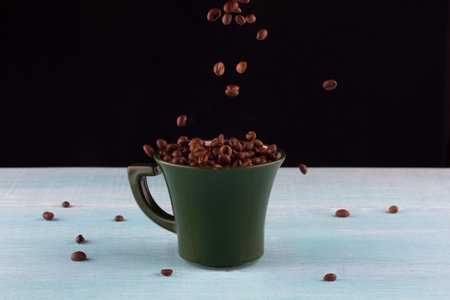 coffee beans pour into a green mugの写真素材