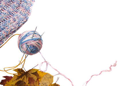 a ball of woolen threads and a knitted scarf with autumn yellow leaves on a white background