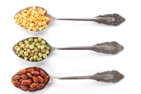 the spoon is filled with green and dried peas and red beansの写真素材