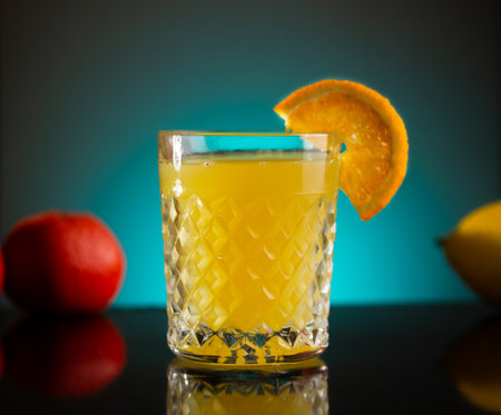 next to a glass of fresh orange juice are lemon and tangerineの写真素材