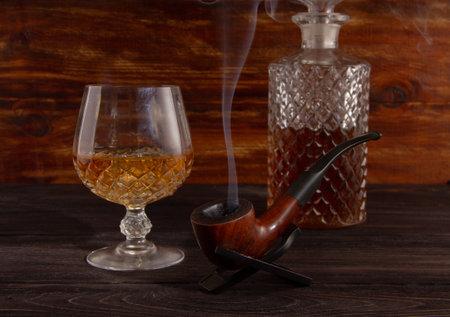 On the table there is a decanter, a glass of whiskey and a smoking pipeの写真素材