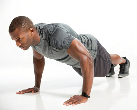 A determined Black man in athletic clothing performs a push-up with focus and strength, showcasing his fitness.の素材