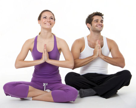 A happy couple, a woman and a man, meditating in the lotus pose with hands pressed together.の素材