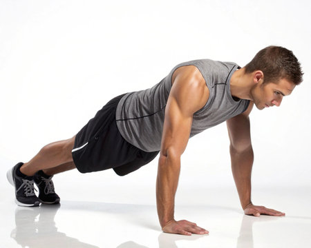 A fit man in athletic wear performs a push-up exercise, demonstrating strength and dedication to his workout routine.の素材