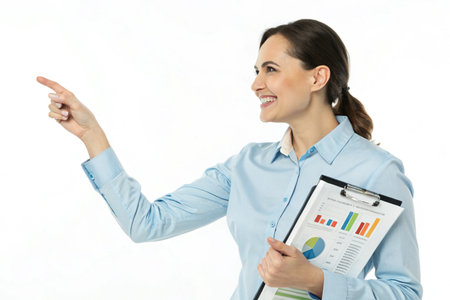 A smiling businesswoman in a blue shirt points to a chart, holding a clipboard with financial data.の素材
