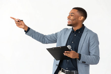 A confident African American man in a suit jacket points forward while holding a clipboard and pen.の素材