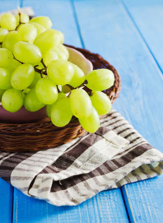 bunch of grapes in a basket on a blue table