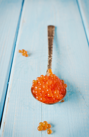 red salmon caviar in spoon on blue backgroundの写真素材