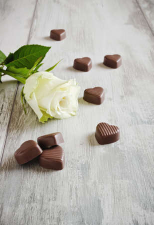 white rose and chocolate hearts on the tableの写真素材
