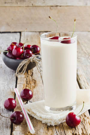 fresh yogurt in a glass and ripe cherries on a wooden background. health and diet foodの写真素材