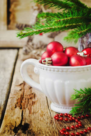 small christmas red balls in an old cup on the old wooden background. selective focusの写真素材