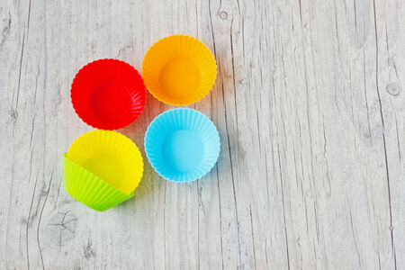 colorful silicone molds for cupcakes on a wooden background. copy space background