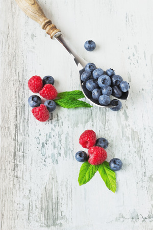 tasty ripe raspberries and blueberries in an old spoon on wooden background.health and diet foodの写真素材