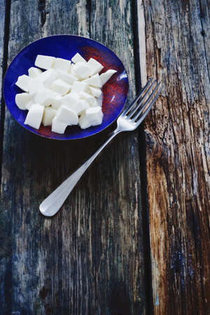 sliced mozzarella cheese in a bowl on the old wooden background.health and diet food.copy space for textの写真素材