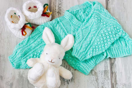 children's knitted sweater, booties and toys on a wooden background. care of childrenの写真素材
