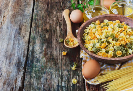 pasta in a wooden bowl, vegetable oil ,spaghetti  and eggs on old wooden background. の写真素材