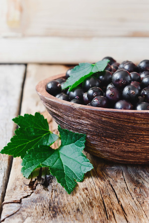 fresh black currant in a wooden bowl on the old wooden background.の写真素材