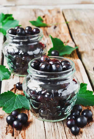 fresh black currant in a glass jar on the old wooden background.の写真素材