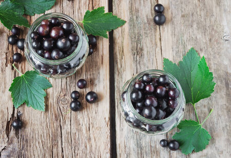 fresh black currant in a glass jar on the old wooden background. の写真素材