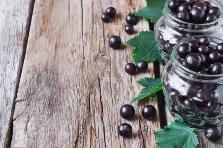 fresh black currant in a glass jar on the old wooden background.の写真素材