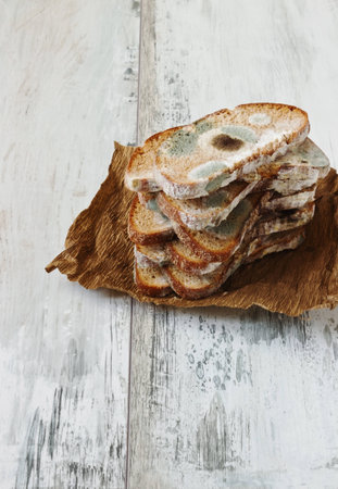 spoiled moldy bread on a wooden background. careless attitude toward foodの写真素材