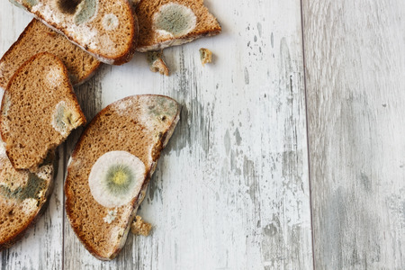 old spoiled moldy bread on a wooden background. careless attitude toward food.の写真素材