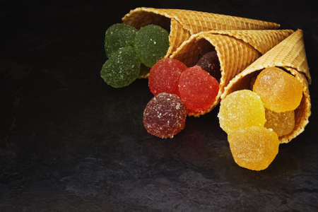 tasty wafer cone with jelly candies on dark background. sweet food.の写真素材