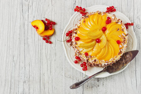 delicious cake with sliced apricots and red currants on a wooden background. festivals and events. view from the topの写真素材