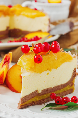 piece of peach cake with red currant berries in a plate on the festive table close up.の写真素材