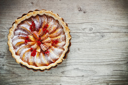 fruit cake with peaches and red currants on a wooden background. sweet breakfast. traditional pastries. view from the top. copy space backgroundの写真素材