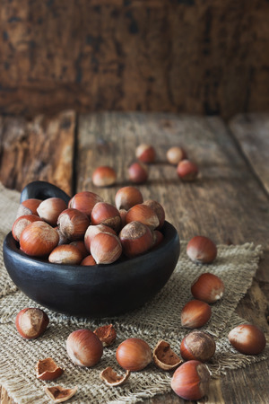 hazelnut in black ceramic bowl on old wooden background. forest wealth. rustic styleの写真素材