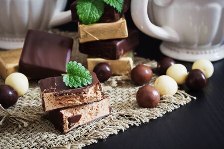 assortment of chocolate candies on a black wooden background. sweet table. selective focus