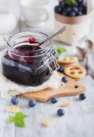 homemade blueberry jam in a jar and fresh blueberries on a tableの写真素材