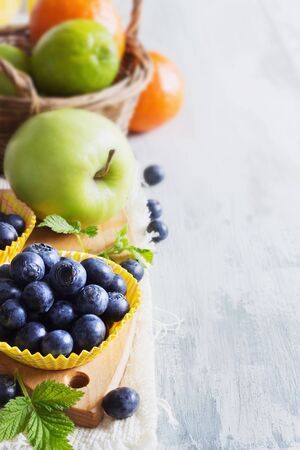 ripe blueberries in a paper cup and various ripe fruit.の写真素材