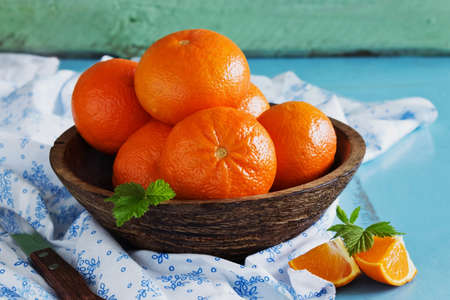 ripe oranges in a wooden bowl on a blue wooden table.の写真素材