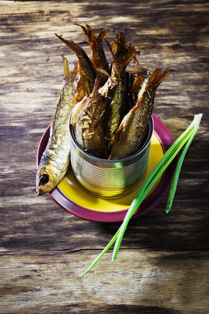 smoked baltic herring in an iron jar on the old wooden background. rustic style. top view. traditional cuisine.の写真素材