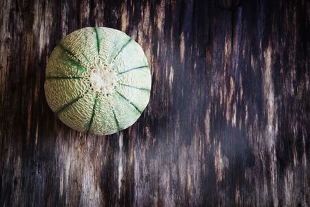 organic small striped melon on a wooden table. close-up. fruits and vegetables from his garden. copy space background.top viewの写真素材