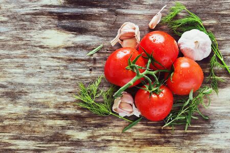 ripe tomatoes and herbs on an old wooden table. healthy food. rustic style. top view. copy space backgroundの写真素材