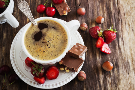 cup of freshly brewed coffee, chocolate and fruit on the old wooden background. rustic style. top viewの写真素材