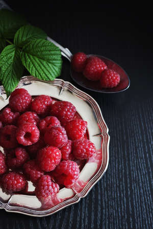ripe juicy raspberries in old metal plates on a black wooden background. from his garden berries. health and diet food. selective focusの写真素材