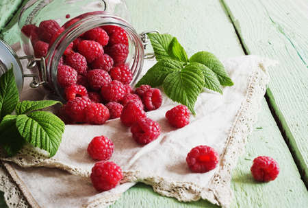 ripe raspberries in a glass jar on a colored wooden background. health and diet food. selective focusの写真素材