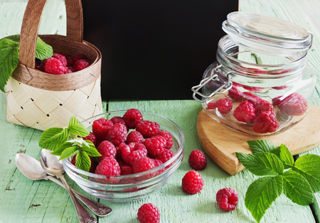 ripe raspberries in a glass jar on a colored wooden background. health and diet concept. selective...