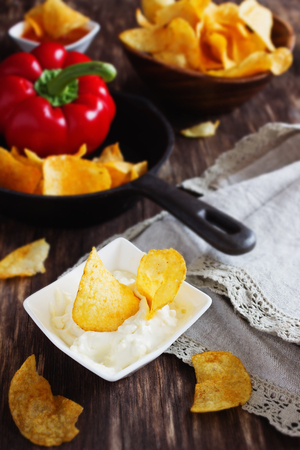 Potato chips and garlic sauce on a wooden table. Unhealthy food. Selective focusの写真素材