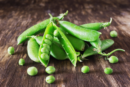 Pods of fresh green peas on vintage wooden table. Organic vegetables.  Rustic style. Selective focusの写真素材