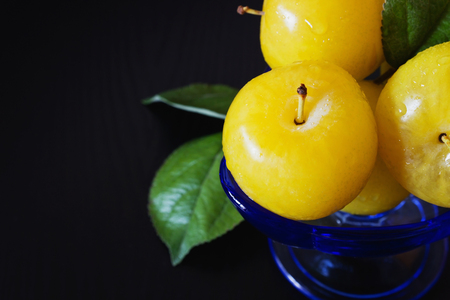 Organic ripe yellow plums in a glass bowl on a black wooden background. Close-up. Bio healthy food. Copy space background.の写真素材