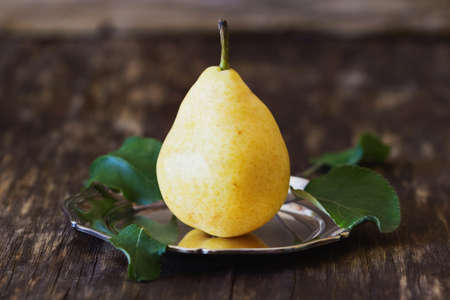 Organic ripe pear in vintage metal plate on a rustic wooden background. Bio healthy food. Selective focusの写真素材